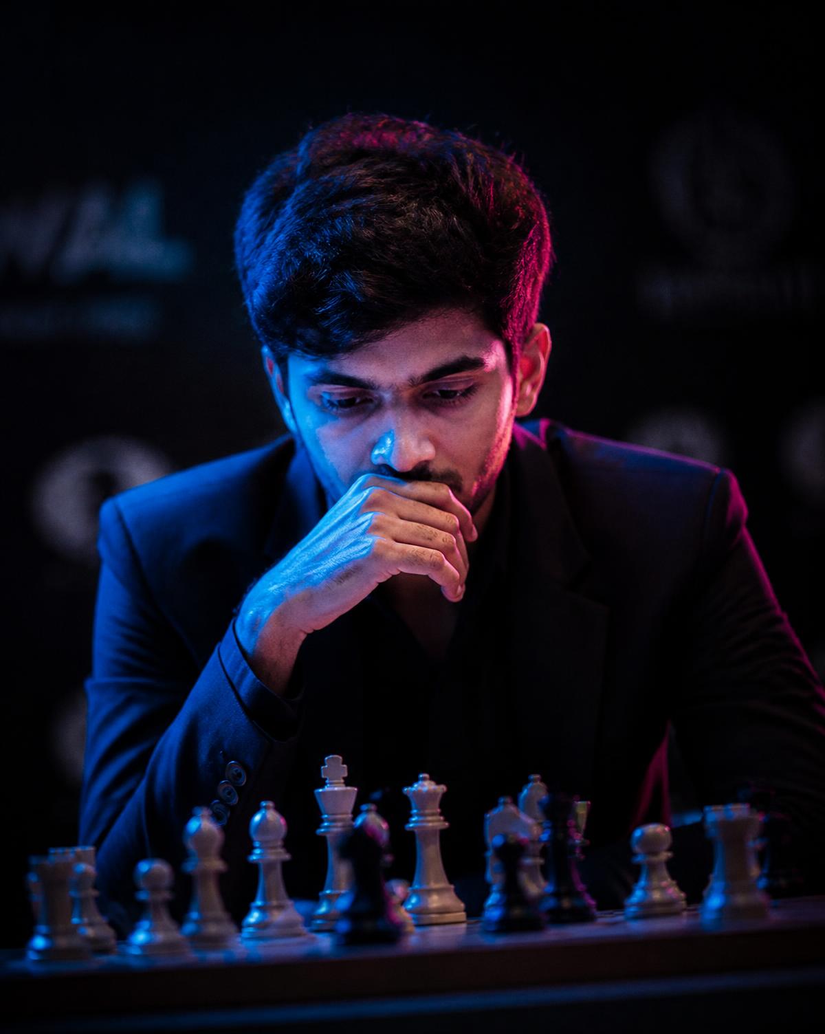 Young Indian player concentrating over a chess board under blue and pink light